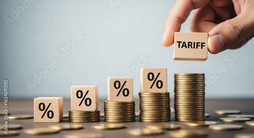 Hand placing tariff block atop percentage blocks and coin stacks showing increasing financial burden