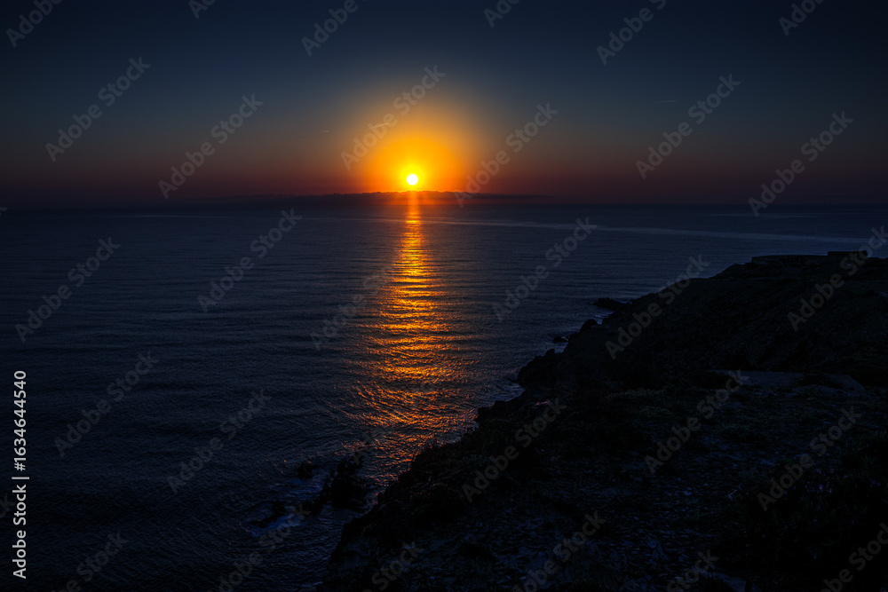 Fototapeta premium Sunrise in Catalan country, at Cap Béar, reflected in the sea surrounded by rocks at Port Vendres in the south of France. 