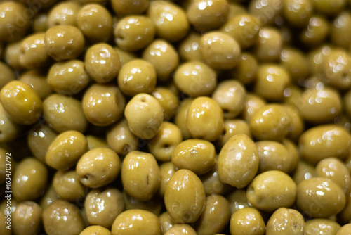 Obraz na plátně Close-up of whole green olives packed tightly together, showing plump forms and smooth skins under soft light