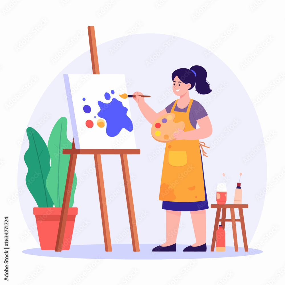 Fototapeta premium A smiling female artist in a yellow apron painting a colorful abstract piece on a canvas at her easel.