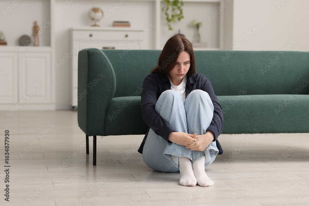 Sad young woman sitting on floor at home Sad young woman sitting on floor at home