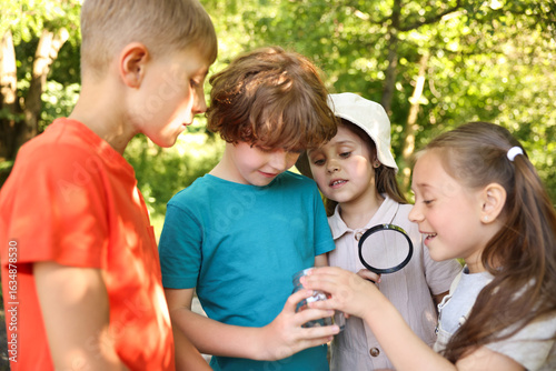 Konstfotografi Children with magnifying glass and jar in nature