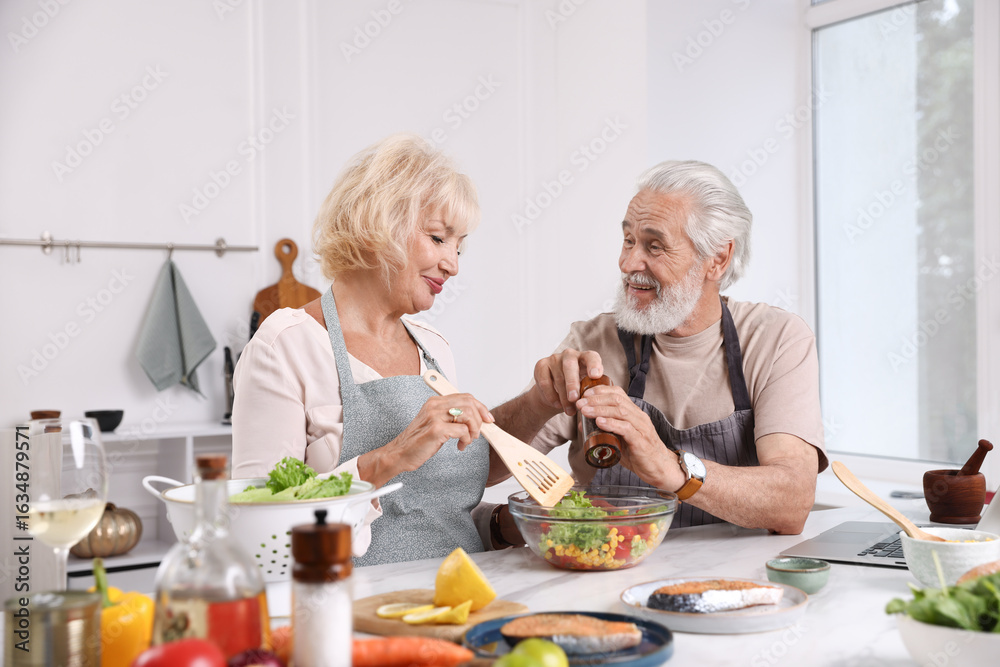 Elderly couple cooking together at table indoors Elderly couple cooking together at table indoors