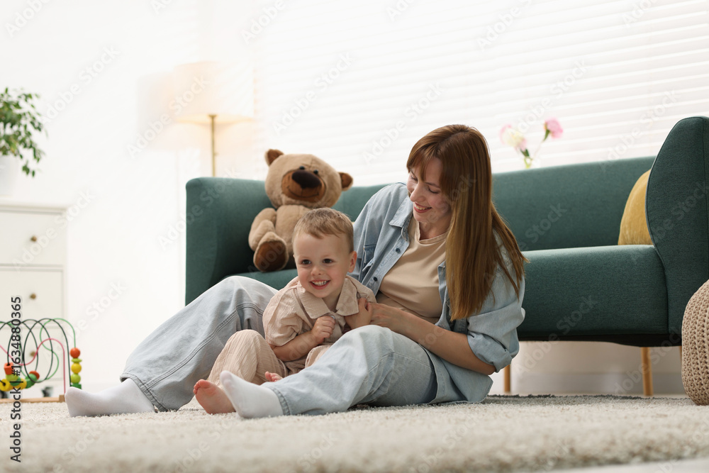 Fototapeta premium Happy mother spending time together with her son on floor at home
