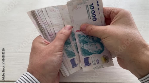 man counting money 10000 argentine pesos bills