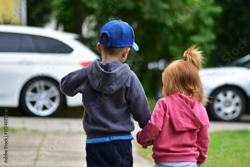 Schilderij op canvas Two toddler siblings walking hand in hand on the street