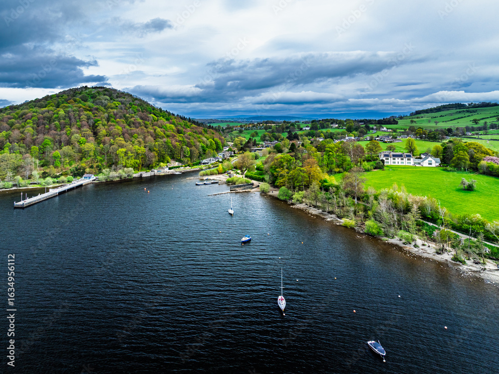 Obraz premium Farms and mountains over Ullswater Lake from drone, Pooley Bridge, Lake District National Park, Cumbria, England