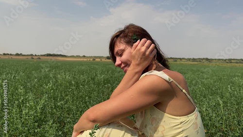 Happy girl sitting in a green field
