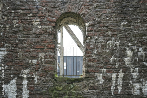 Magpie Mine, The Peak District, England - August 6 2025: Weathered stone arch window with moss and iron bars at Magpie Mine.