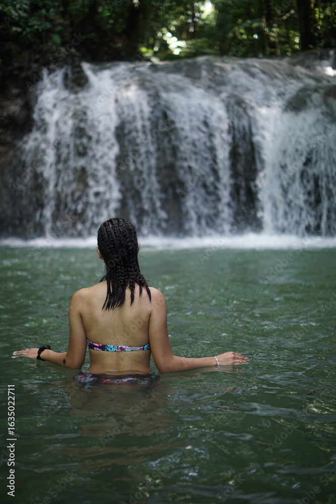 Fototapeta premium Female tourists exploring Siete Altares, which is a natural attraction located near Livingston, Guatemala, featuring seven freshwater pools and waterfalls set within a lush rainforest.