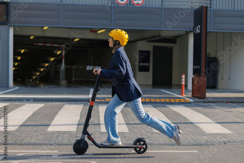 Young woman rides electric scooter on urban street wearing helmet
