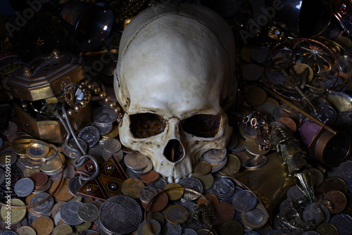 фотографія Dark Image with skull among treasure coins and jewellery.