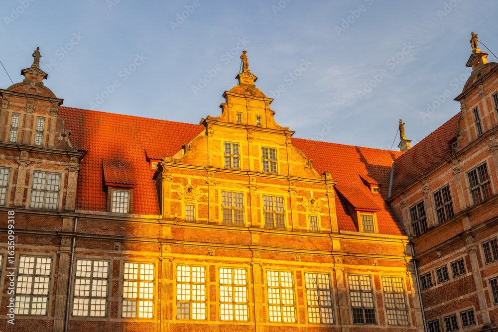 Obraz premium Gdansk, a city on the Baltic coast of northern Poland, Europe. Picturesque architecture with red roofs and golden sunlight on building facades. A captivating urban scene blending history and warmth.