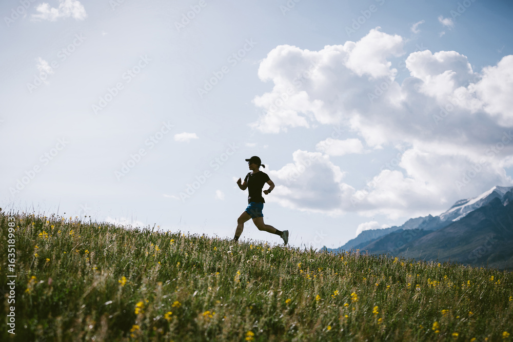 Trail runner running on the high altitude grassland mountain trail Trail runner running on the high altitude grassland mountain trail