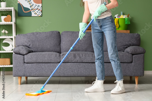 Young woman mopping wooden ...