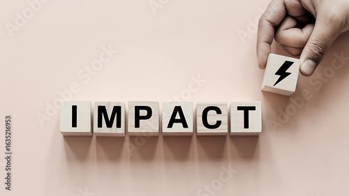 Hand placing a lightning bolt symbol block on the word impact spelled out with letter blocks