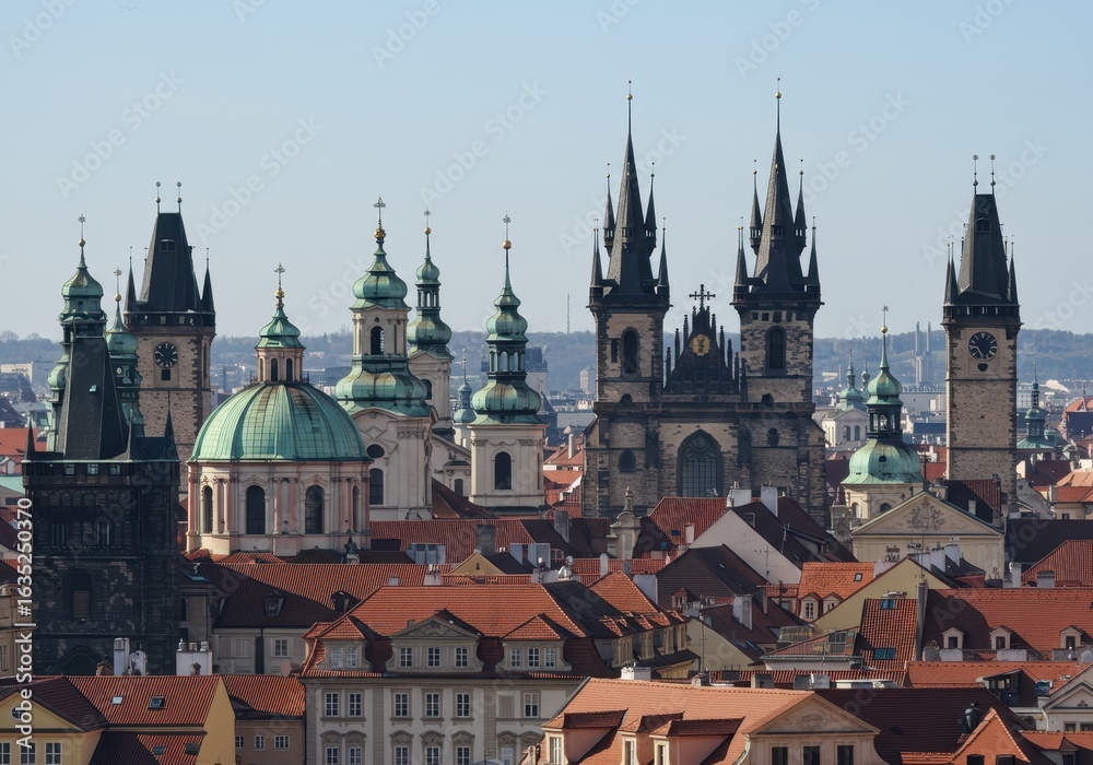 Fototapeta premium Prague cityscape with historic churches and red rooftops under a clear sky
