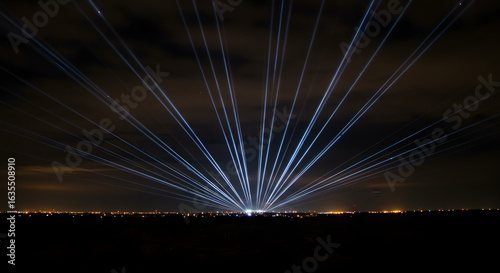 Spectacular laser display illuminating the night sky over urban cityscape horizon