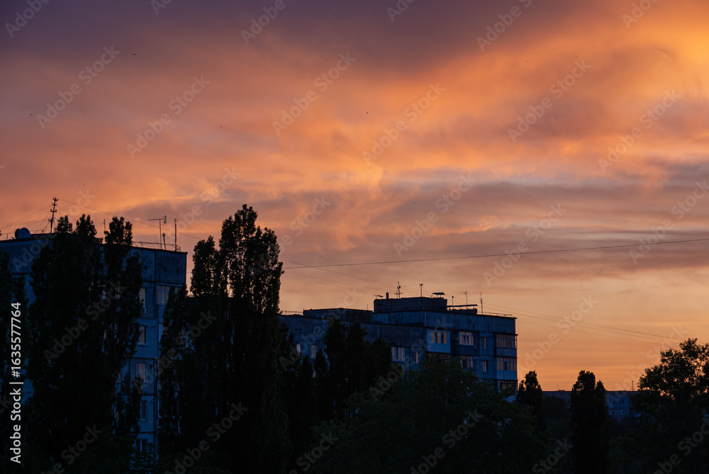 Fototapeta premium Sunset over Soviet-era apartment buildings and trees