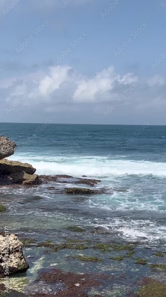 Mbuluk beach rocky shoreline meeting the ocean under a cloudy sky creates a tranquil scene. Mbuluk beach rocky shoreline meeting the ocean under a cloudy sky creates a tranquil scene.