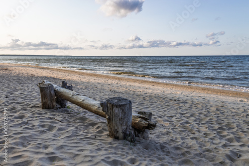 Fototapeta Naklejka Na Ścianę i Meble -  Tranquil Baltic Sea Shore at Sunset with Driftwood Bench and Gentle Waves