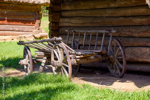 old wooden cart with large wheels standing near a wooden Ukrainian house in the yard