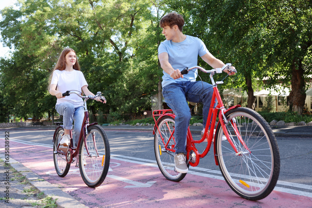 Obraz premium Teenage girl and boy riding bicycles on city street
