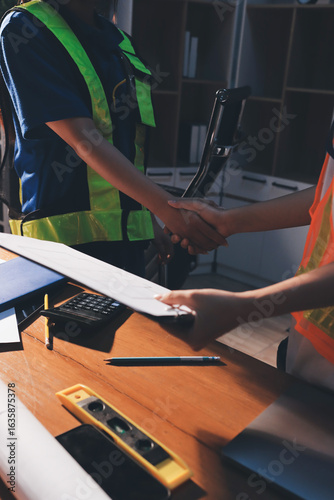 Closeup of team of industrial engineers meeting analyze machinery blueprints consult project on table in manufacturing factory. Working in manufacturing plant or production plant.
