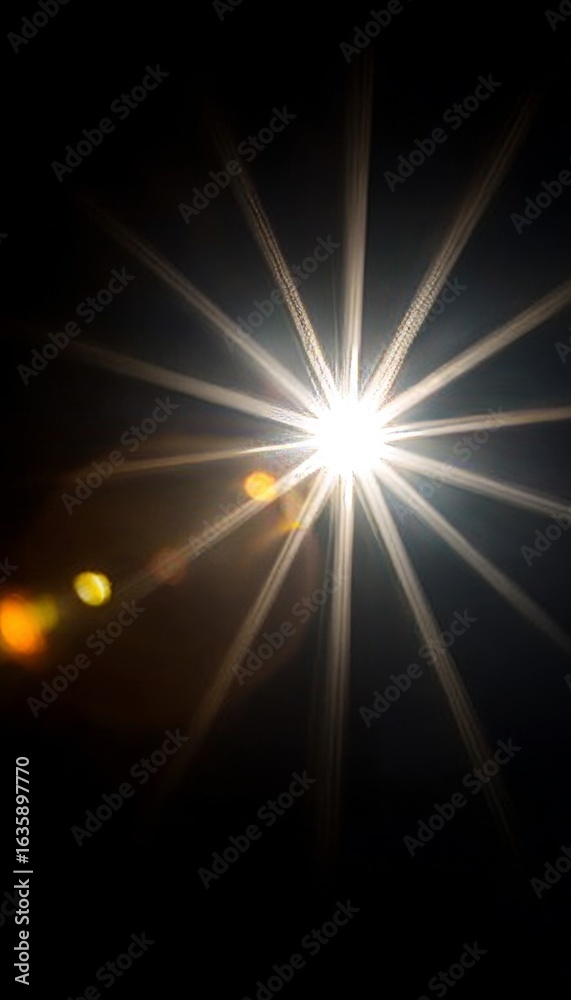 Fototapeta premium Starburst lens flare illuminating a dark canvas, creating a celestial and bright abstract feel.