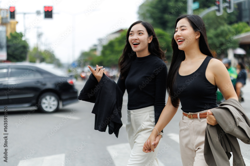 Obraz premium Two businesswomen holding hands while walking in the city