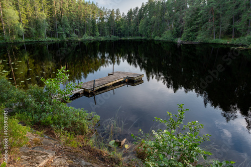 Calm forest lake with small jetty for fishing