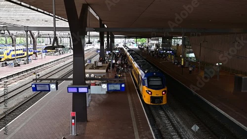 ROTTERDAM, NETHERLANDS, August 1, 2025. Yellow and blue NS trains on the platform of Rotterdam Central Station with passengers and modern canopy. 