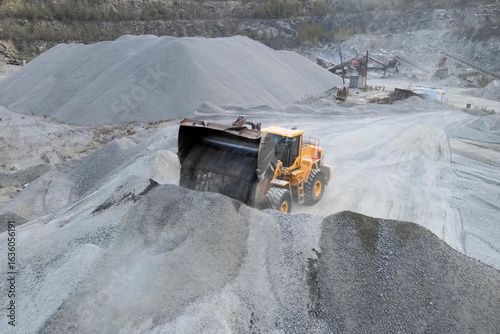 Work of a bulldozer in quarry for the extraction of migmatites and crushed stone.