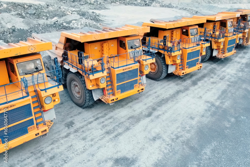 Mining dump trucks are parked in row. Equipment for an industrial quarry.