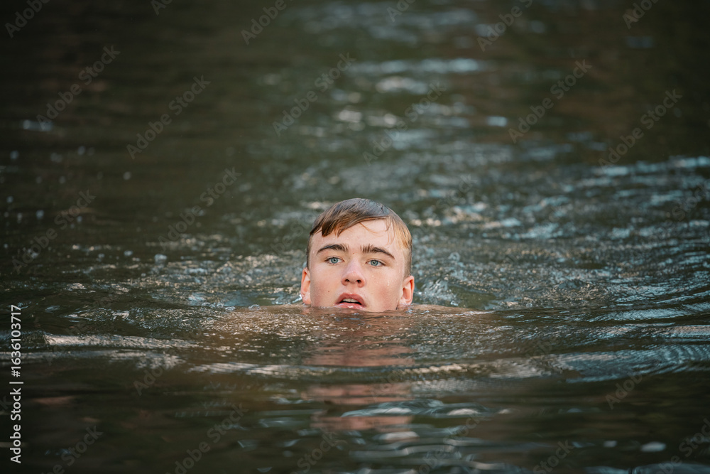 Fototapeta premium Teenage boy swimming in river on summer day