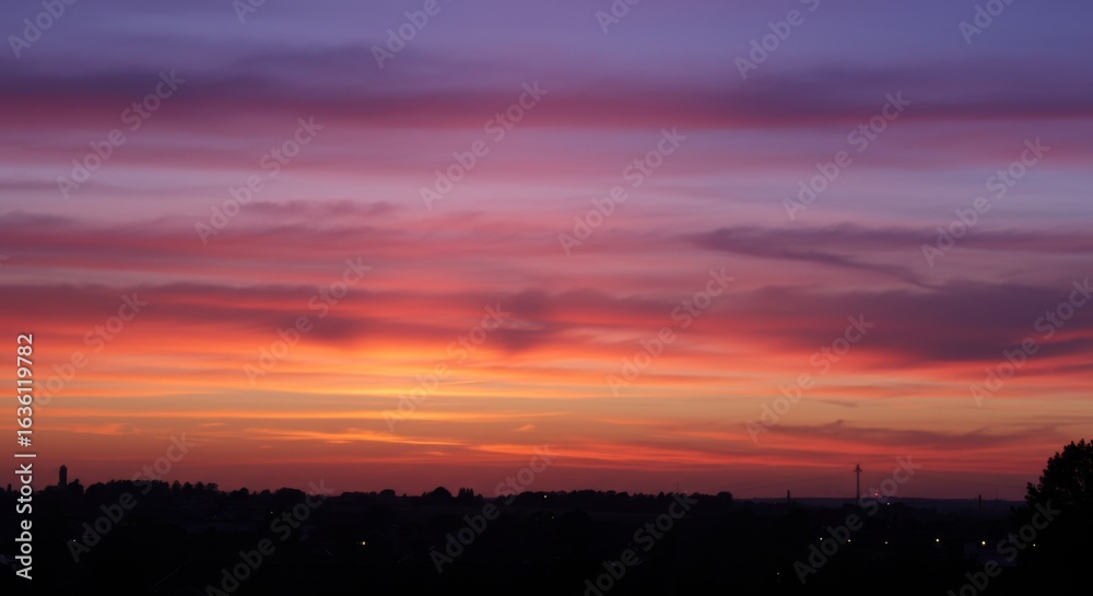 Fototapeta premium Vibrant Sunset Colors Over City Silhouette
