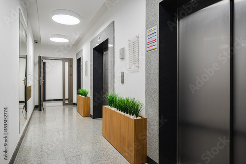 Modern hallway with elevators and planters in a contemporary building setting during daylight