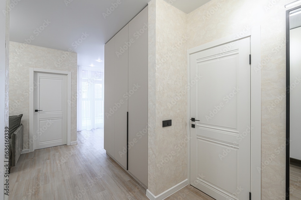 modern hallway showcases a built-in wardrobe, white doors with black hardware, textured walls, and light wood flooring, offering a clean and minimalist design modern hallway showcases a built-in wardrobe, white doors with black hardware, textured walls, and light wood flooring, offering a clean and minimalist design