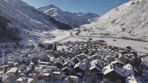 Andermatt, Switzerland in Winter. Aerial of mountain village in Swiss alps in Canton Uri on sunny day after snow fall. 