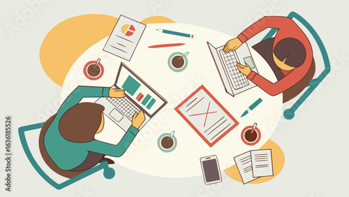 Top view of two people working on laptops with coffee and documents on a round table in an office space