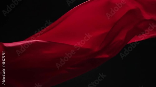 Close up of a flowing red fabric against a dark background creating a dramatic and elegant feel