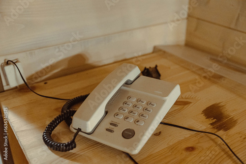 Canvas Print White corded telephone resting on wooden desk in room