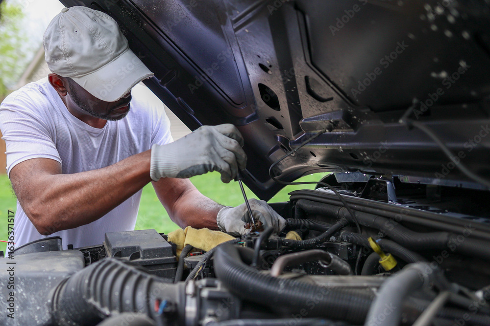 Fototapeta premium A portrait of a black man installing a car battery