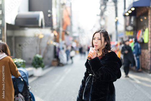 都会の路地でドリンクを楽しむ若い日本人女性