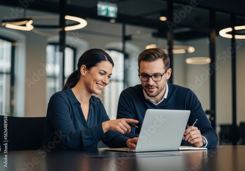 Two Business Colleagues Collaborating on a Laptop in a Modern Office Setting Exuding Professionalism and Teamwork