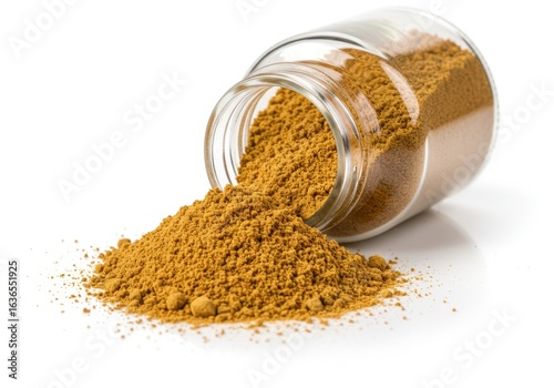 Yellow spice powder spilling from a glass jar, isolated on white background