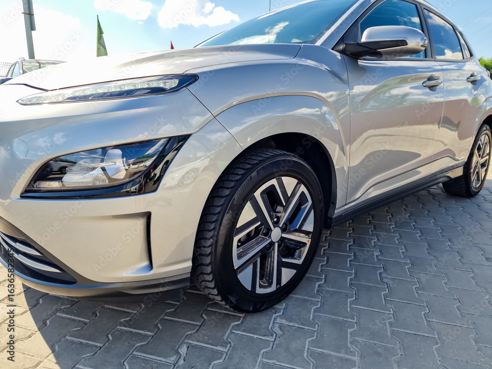 Naklejka premium A sleek silver car with a contemporary design and gleaming alloy wheels is parked elegantly in the driveway, showcasing a blend of elegance and innovative automotive style that captivates the eye