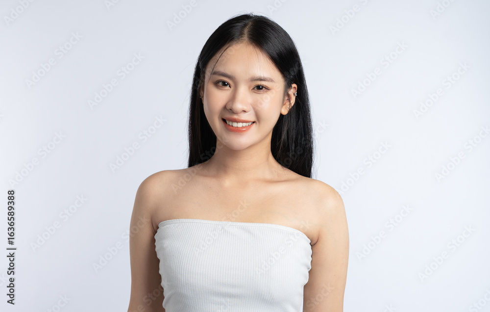 Portrait of a smiling young woman with long dark hair wearing a tube top against a white backdrop Portrait of a smiling young woman with long dark hair wearing a tube top against a white backdrop