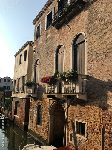 Venetian houses with green shutters facing a canal.
