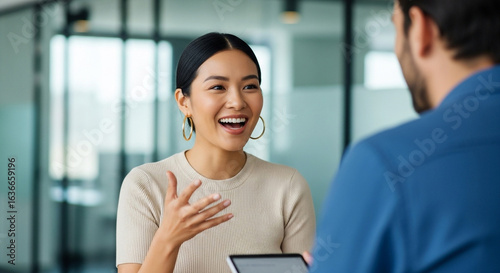 A happy businesswoman gestures while having a positive and engaging discussion with her male colleague. Perfect for illustrating effective team communication